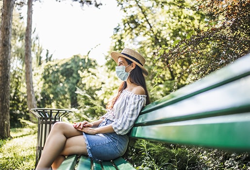 Woman in a mask on a park bench