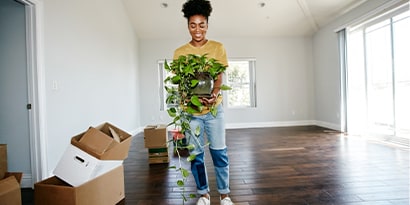 New homeowner holding a plant in an empty room