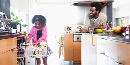 Family in kitchen emptying dishwasher