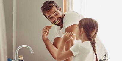 Father and daughter brushing their teeth together