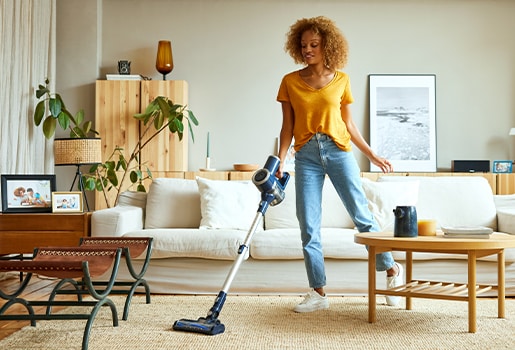 Use your five senses to help determine what to clean next. A woman vacuuming a living room.