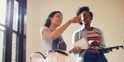 Two women painting a wall together