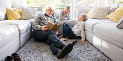 person sitting on the carpet reading a book to children