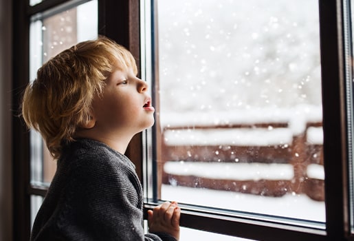 Test your cold weather knowledge and find out how to keep your home comfortable when temperatures drop. Little boy watching snow fall out a window.