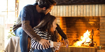 a couple sitting next to a fireplace.