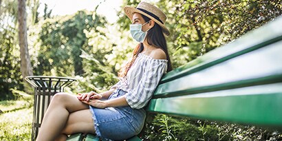A woman sitting outside on a park bench.
