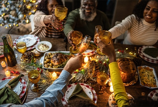 Family eating a holiday meal together smiling and cheering glasses.