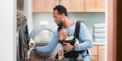 a man doing laundry holding a baby