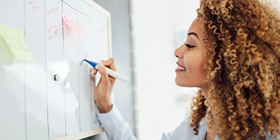 Woman writing on a white board calendar