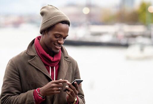 A man looking at his phone outside in the winter