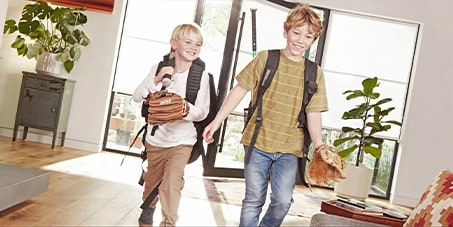 Two children with backpacks and baseball gloves