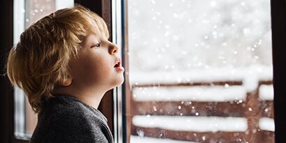 A child looking out a wintery window.

