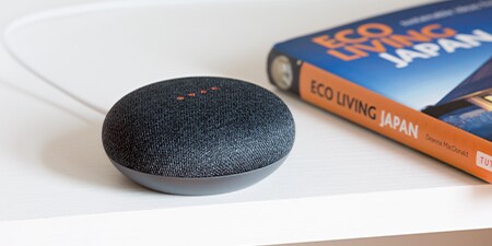  A smart speaker on a table next to a book.
