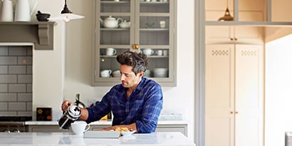 a man pouring a cup of coffee from a french press