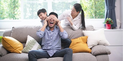 Man playing smiling and playing with family on the couch