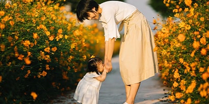 Woman holding hands with a child in a field of flowers