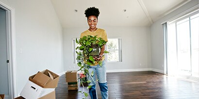 A woman holding a plant in an empty room