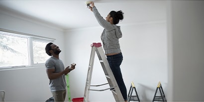 a woman on a ladder replacing a lightbulb.