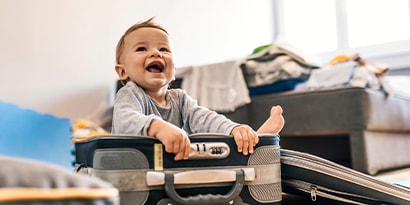 a baby smiling sitting in a suitcase