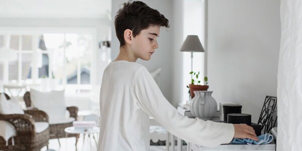 A boy wiping down a surface in the home.
