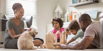 Dog sitting with a family playing with blocks.