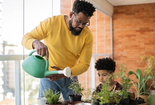 Keep the cleaner air coming all year long with these 10 tips. A man watering a plant, his son next to him.