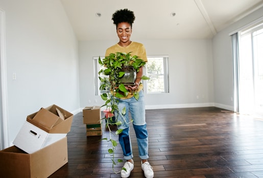 Lady moving in to new home. Woman holding plant, moving in to new home.
