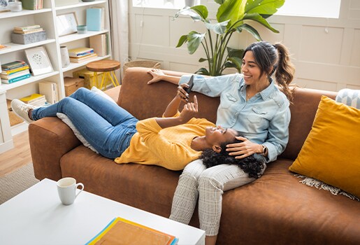 IThese seven apps will help you stay more organized in the new year. Two women sitting on a couch, one is on her phone.