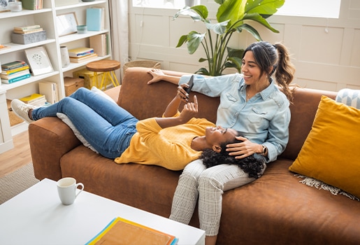 IThese seven apps will help you stay more organized in the new year. Two women sitting on a couch, one is on her phone.