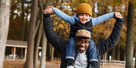 Joyful man with child on shoulders