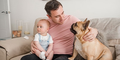 A man sitting with a baby and a dog