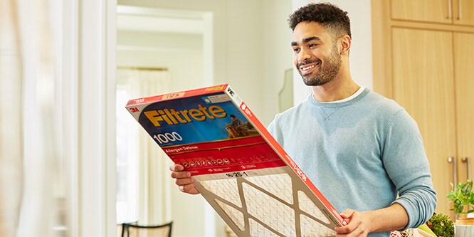 Mother changing a Filtrete™ room air purifier filter in a baby nursery

