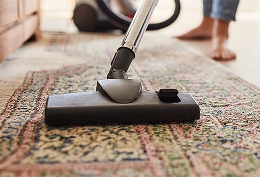 Consult our top tips for affordable ways to improve your indoor air. Close up of a vacuum being used on a rug.