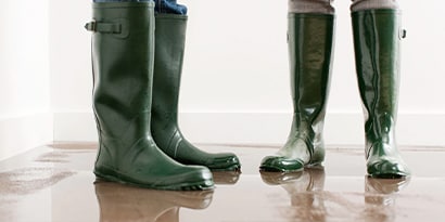 Two pairs of rain boots in a puddle