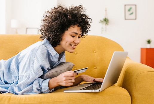 In the market for an air filter for your home? We've rounded up six things you should consider before you shop. A woman lounging on a couch holding a credit card and entering information into a laptop.