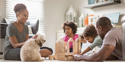 a family playing with blocks on the floor with the family dog