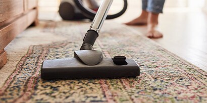 A close up of a rug being vacuumed.
