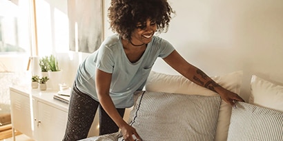 a woman smiling and making the bed