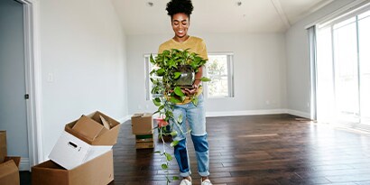 Build confidence and make the most of your first home with these seven essential to-dos. A woman holding a potted plant.
