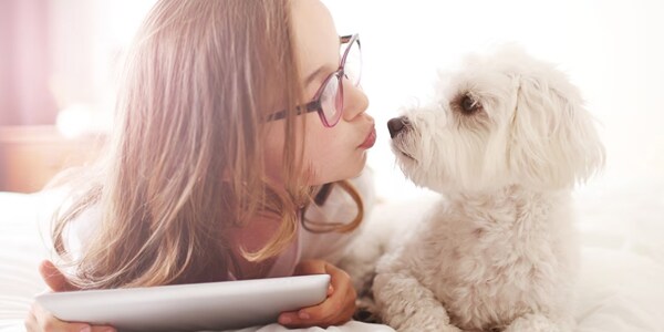 Woman making a kiss face at a white fluffy dog
