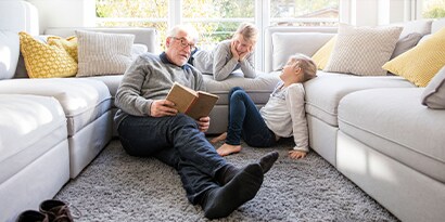 a man sitting on the floor reading to two children.
