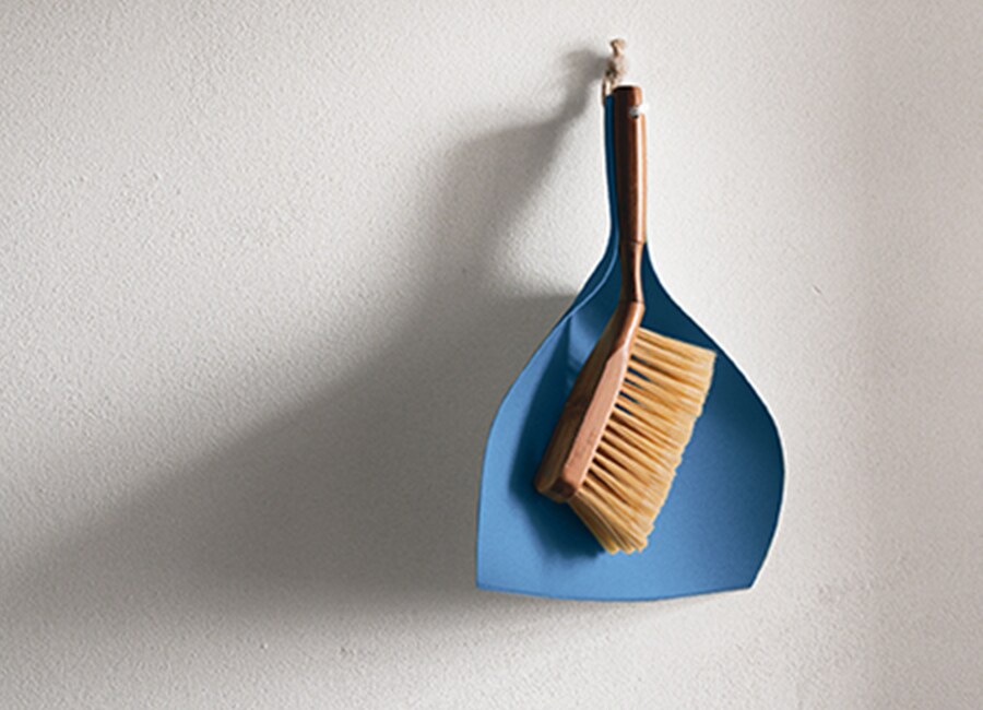 Blue Dust Pan and Broom Hanging on Wall
