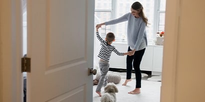 Looking through a door into a room, a mother dances with a child.
