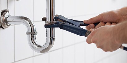 Hands doing plumbing work on a sink.
