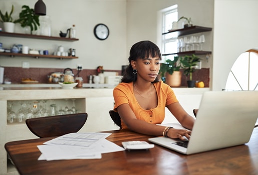 Five ways to make tidying and disinfecting your desk part of your cleaning routine. Woman using a laptop at a desk.