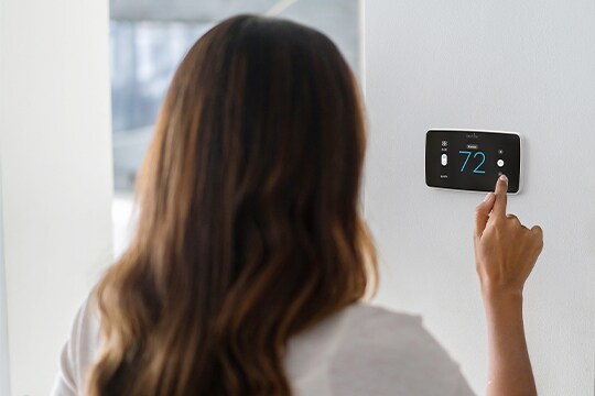 A woman using a Sensi Smart thermostat.
