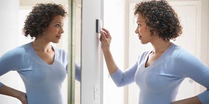 A woman using the thermostat.
